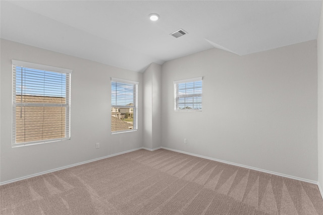 empty room with baseboards, carpet, lofted ceiling, and visible vents