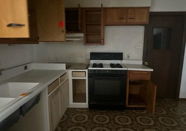 kitchen featuring open shelves, gas range oven, light countertops, under cabinet range hood, and a sink