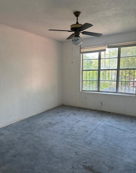 empty room with a ceiling fan, a textured ceiling, and carpet flooring