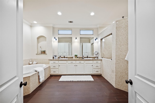 full bath with a sink, ornamental molding, double vanity, and wood finished floors