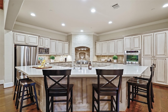 kitchen with visible vents, a large island, light countertops, appliances with stainless steel finishes, and backsplash