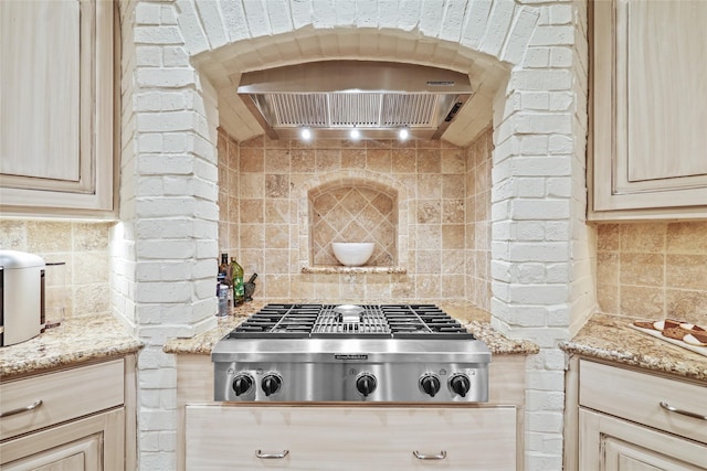 kitchen featuring custom exhaust hood, stainless steel gas cooktop, backsplash, and light stone countertops