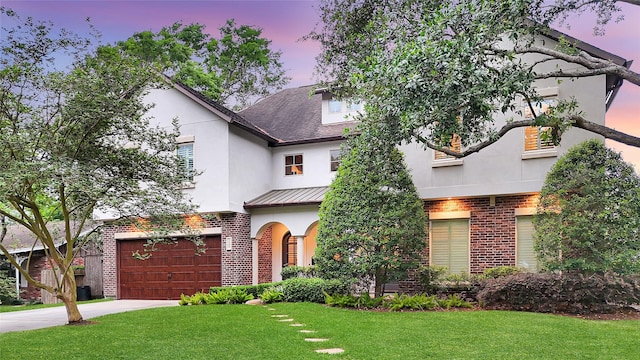 view of front of house featuring a garage, a front yard, stucco siding, brick siding, and concrete driveway