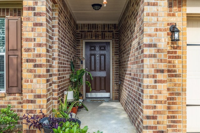 doorway to property with covered porch and brick siding