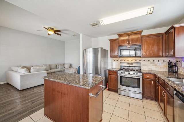 kitchen featuring visible vents, ceiling fan, a center island, dark stone countertops, and appliances with stainless steel finishes