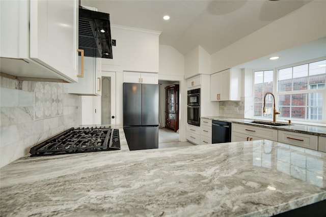 kitchen with light stone counters, a sink, white cabinetry, vaulted ceiling, and black appliances