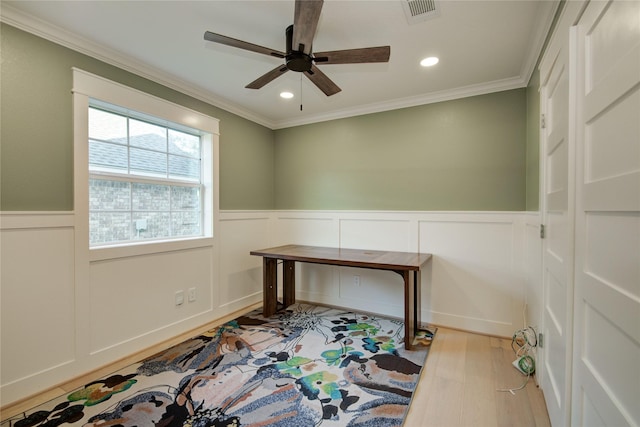 unfurnished office featuring ceiling fan, visible vents, crown molding, wainscoting, and wood finished floors