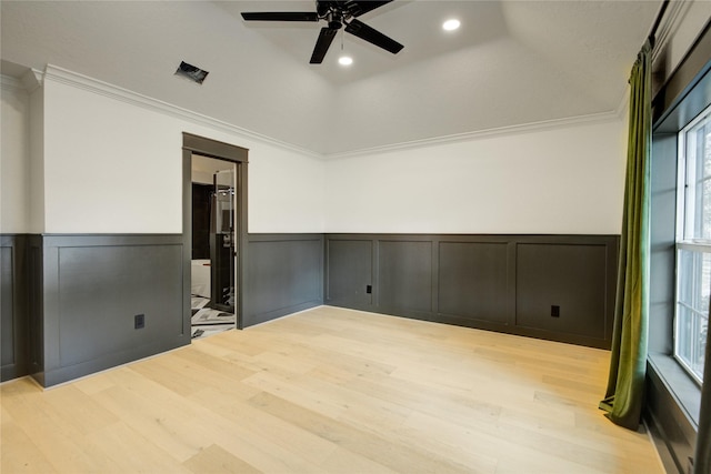 unfurnished room featuring ceiling fan, wainscoting, light wood-style floors, and a decorative wall