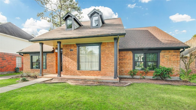 view of front of house featuring brick siding, a front lawn, and roof with shingles
