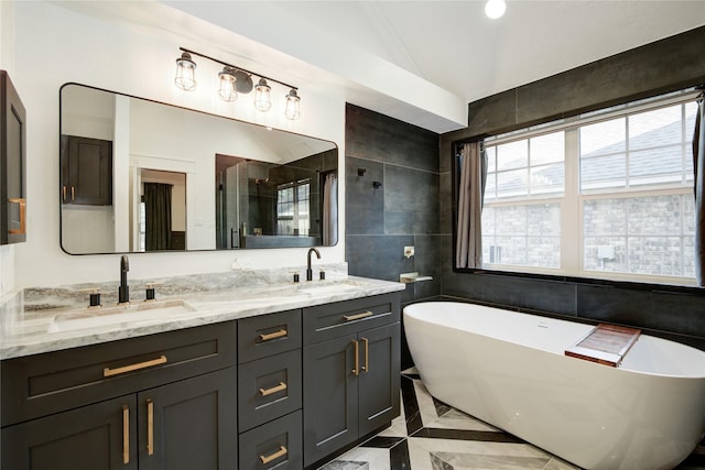bathroom featuring a sink, tile walls, double vanity, and a freestanding bath
