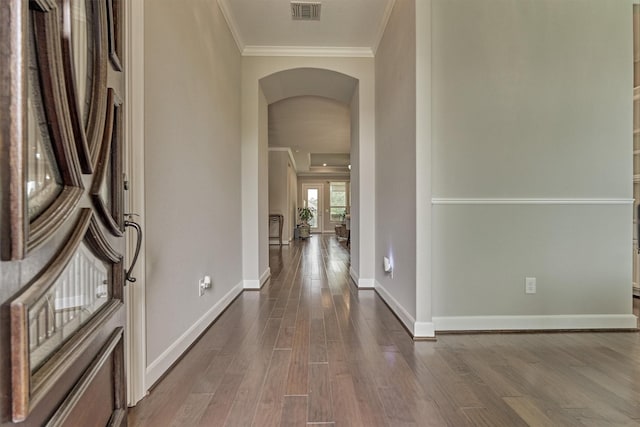 hall with visible vents, crown molding, arched walkways, baseboards, and dark wood-type flooring