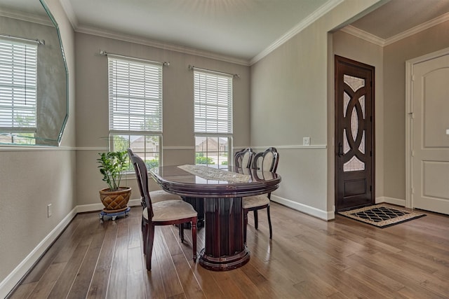 dining space featuring crown molding, baseboards, and wood finished floors