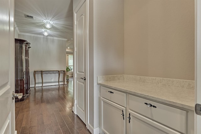 hall with visible vents, ornamental molding, and dark wood-style flooring