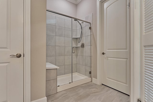 bathroom featuring crown molding, marble finish floor, and a shower stall