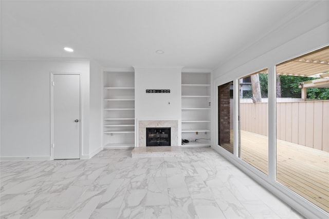unfurnished living room with crown molding, built in features, marble finish floor, recessed lighting, and a premium fireplace