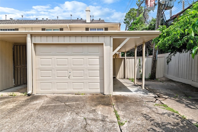 garage featuring fence and concrete driveway