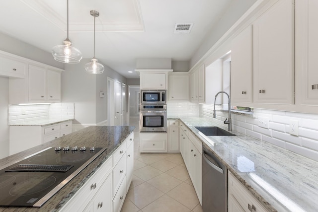 kitchen featuring appliances with stainless steel finishes, a sink, tasteful backsplash, and white cabinets