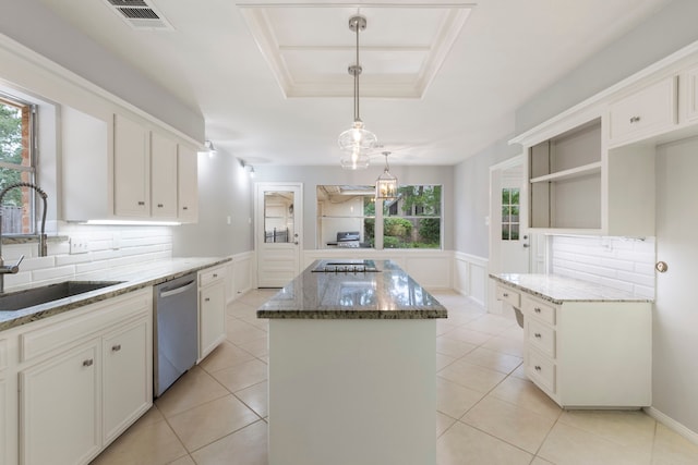 kitchen featuring dishwasher, a sink, a center island, a raised ceiling, and dark stone countertops