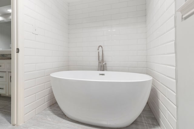 bathroom featuring a soaking tub, tile walls, and vanity