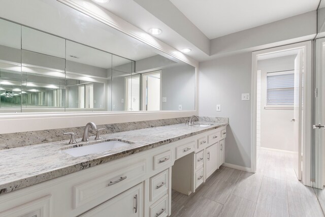 bathroom with double vanity and baseboards
