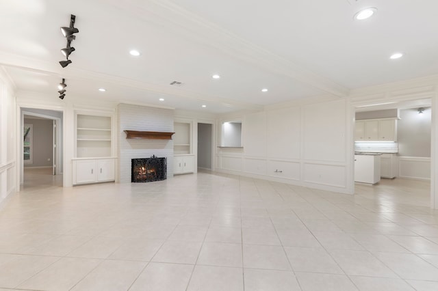 unfurnished living room featuring ornamental molding, a decorative wall, built in features, light tile patterned floors, and a fireplace