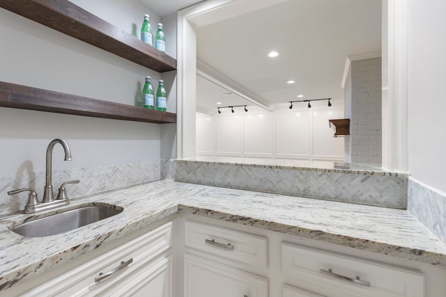 kitchen featuring open shelves, a sink, light stone countertops, and white cabinets