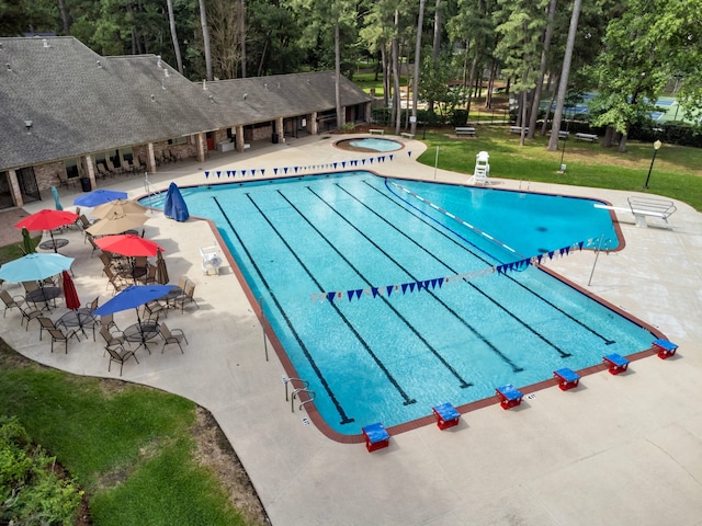 community pool featuring a hot tub, a patio, and a lawn