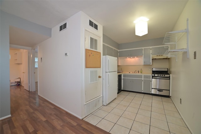 kitchen with stainless steel gas range, a sink, visible vents, and freestanding refrigerator