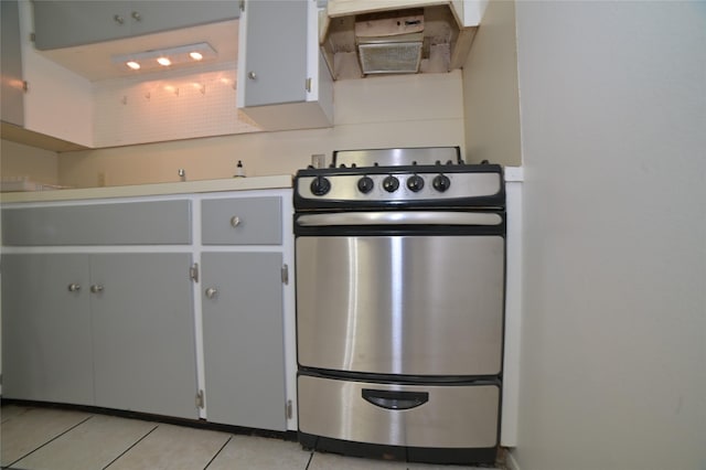 kitchen featuring under cabinet range hood, stainless steel range with gas stovetop, light tile patterned floors, and light countertops