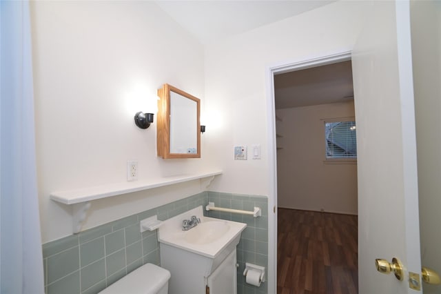 bathroom with vanity, toilet, a wainscoted wall, tile walls, and wood finished floors
