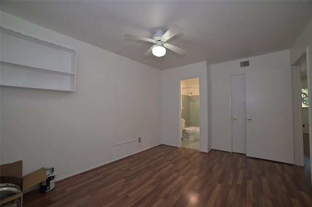 unfurnished bedroom featuring ceiling fan, visible vents, dark wood finished floors, and ensuite bathroom