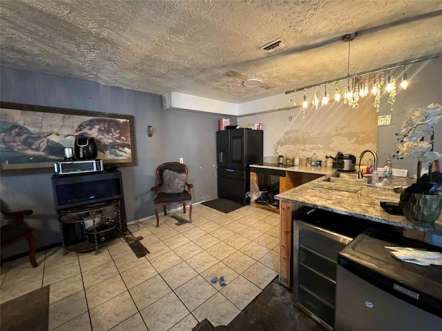 kitchen featuring light tile patterned flooring, a sink, a textured ceiling, stainless steel microwave, and visible vents
