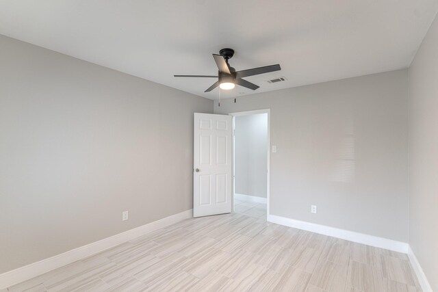 empty room with baseboards, a ceiling fan, visible vents, and light wood-type flooring
