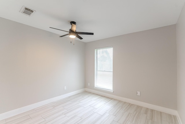 spare room with ceiling fan, visible vents, and baseboards