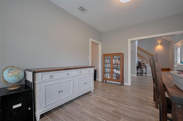 corridor with baseboards, visible vents, light wood-style flooring, and stairway