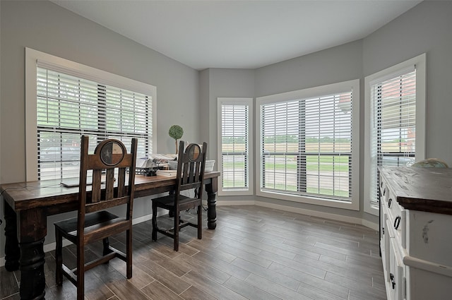 dining space featuring baseboards, dark wood-style flooring, and a healthy amount of sunlight