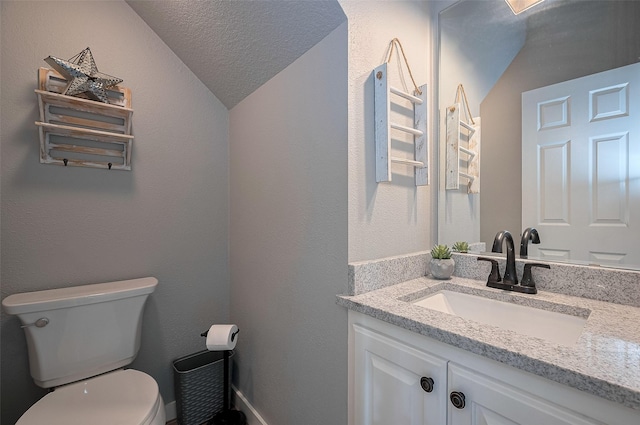 half bathroom with vanity, a textured ceiling, lofted ceiling, and toilet