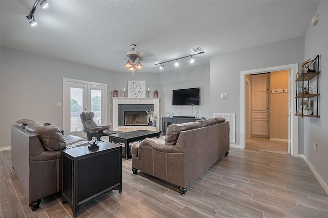 living room featuring a ceiling fan, track lighting, and light wood finished floors