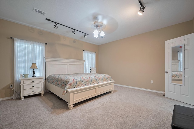 bedroom featuring visible vents, rail lighting, carpet, and baseboards