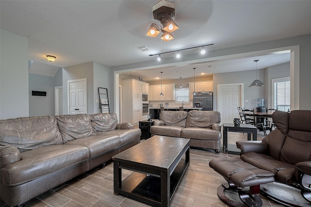 living area featuring ceiling fan, visible vents, plenty of natural light, and light wood-style flooring