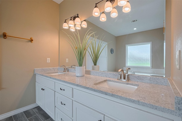 bathroom featuring a sink, baseboards, double vanity, and visible vents