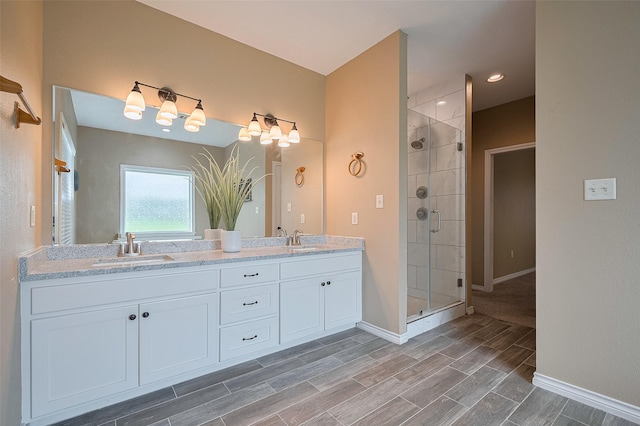 bathroom with baseboards, a sink, a stall shower, and double vanity