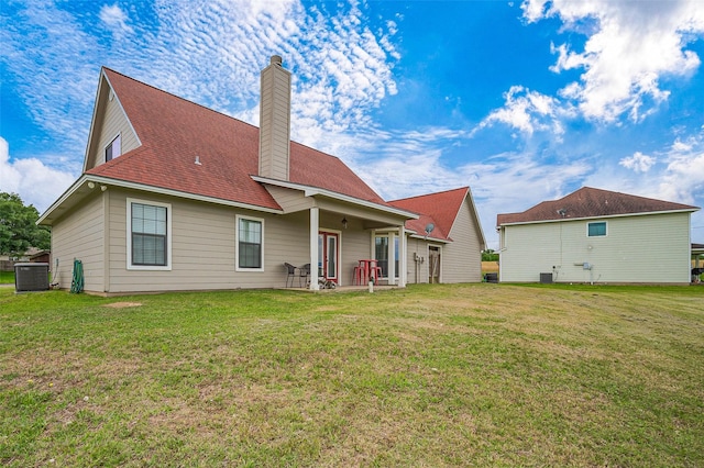 rear view of house featuring a lawn, a chimney, and central AC