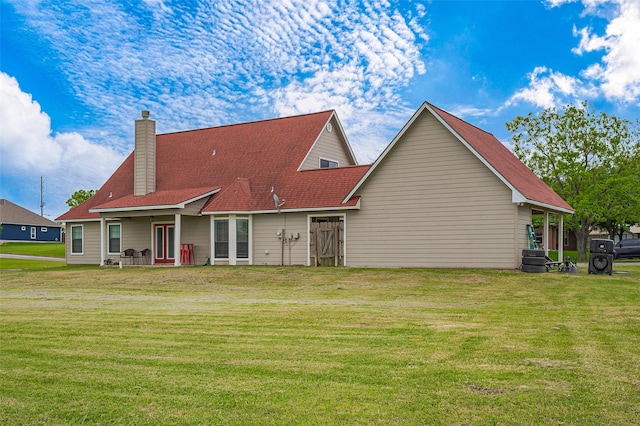 back of property with a chimney and a yard