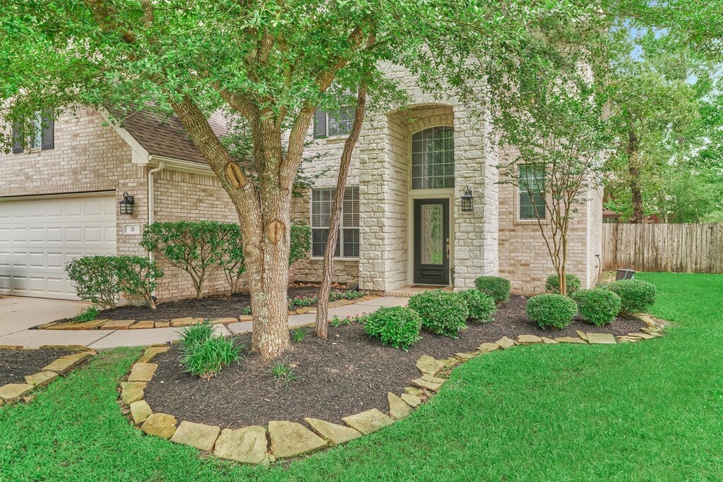 view of front of house with fence, a shingled roof, brick siding, and a front yard