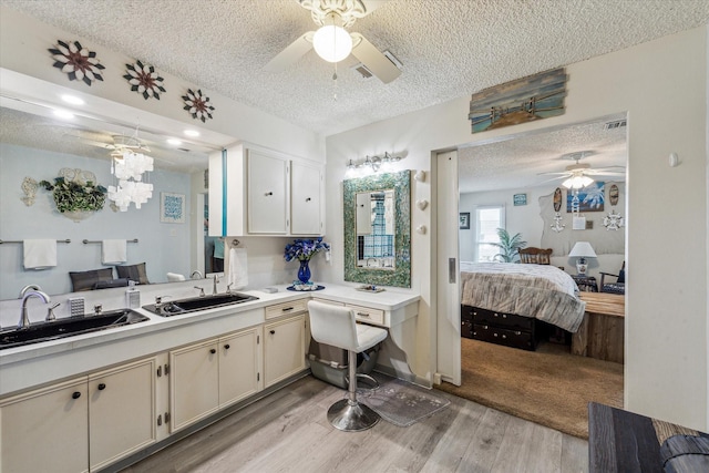ensuite bathroom with a textured ceiling, ceiling fan, a sink, and ensuite bathroom