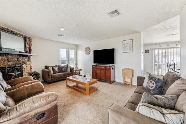 living room featuring a stone fireplace, light colored carpet, a textured ceiling, and visible vents