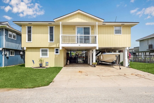 view of front facade with fence, a carport, concrete driveway, and a front lawn