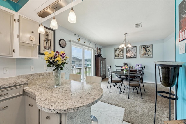 interior space with an inviting chandelier, hanging light fixtures, a peninsula, and visible vents