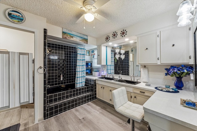 bathroom with a textured ceiling, tiled shower / bath, a ceiling fan, and wood finished floors